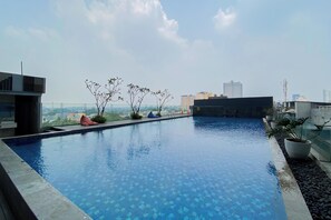 Ein Dachpool mit freiem Blick auf die Stadtlandschaft, umgeben von Topfpflanzen und moderner Architektur.