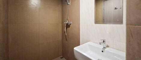 Un baño con ducha, lavamanos y espejo.