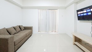 Un salon moderne avec un canapé, un téléviseur fixé au mur et une porte-fenêtre coulissante.