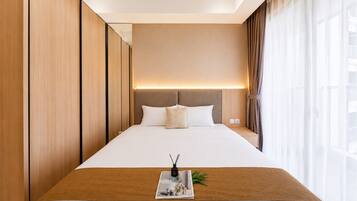 Habitación de hotel con una cama grande, una mesita de noche, cortinas en la ventana y una lámpara de pared.