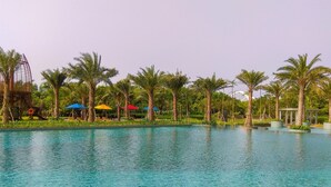 Una piscina con palmeras y sombrillas.
