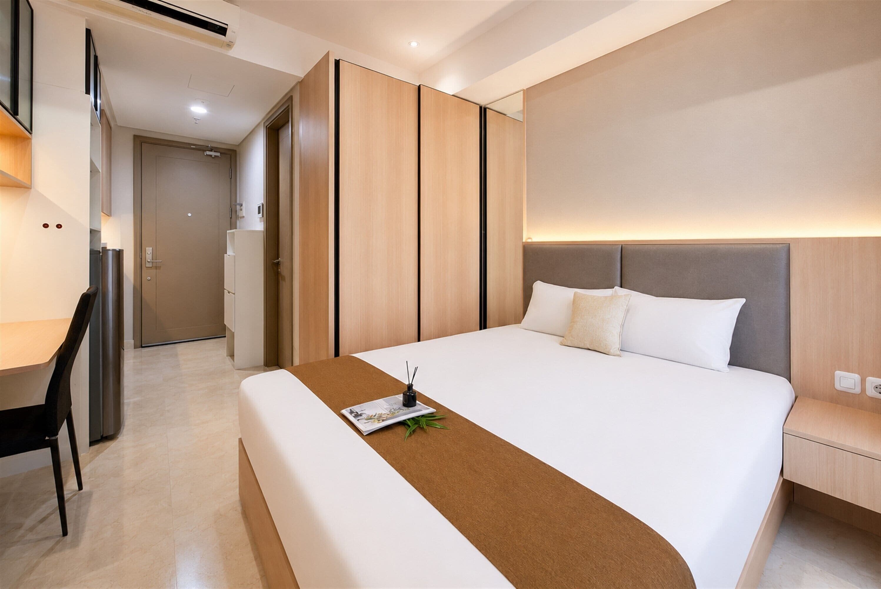 Moderni hotellihuone, jossa on suuri sänky, työpöytä ja vaatekaappi.