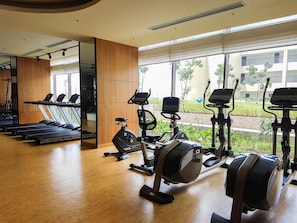 Ein Fitnessstudio mit Laufbändern, Crosstrainern und Holzboden.