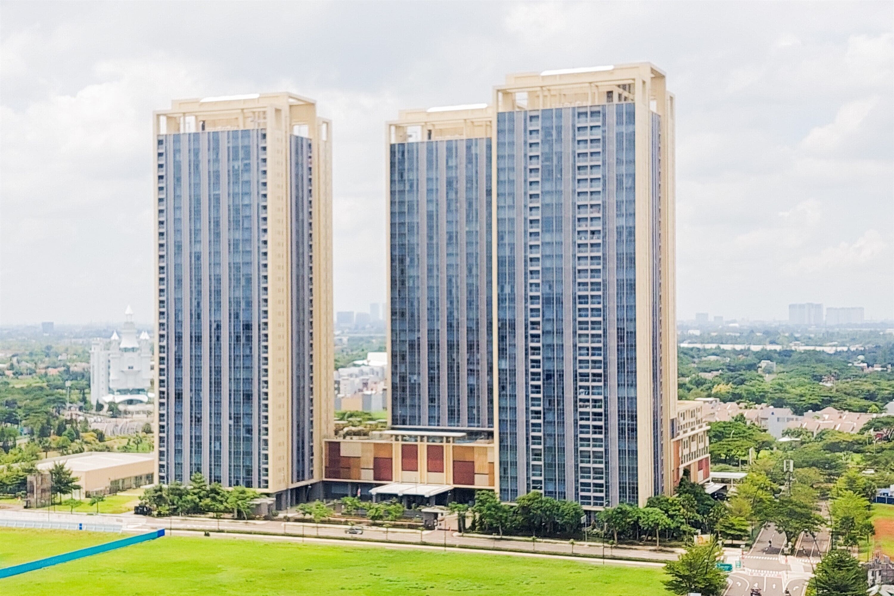 Two high-rise buildings with a sports field in the foreground.