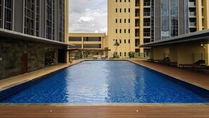 Piscina rodeada por edifícios modernos sob um céu claro.