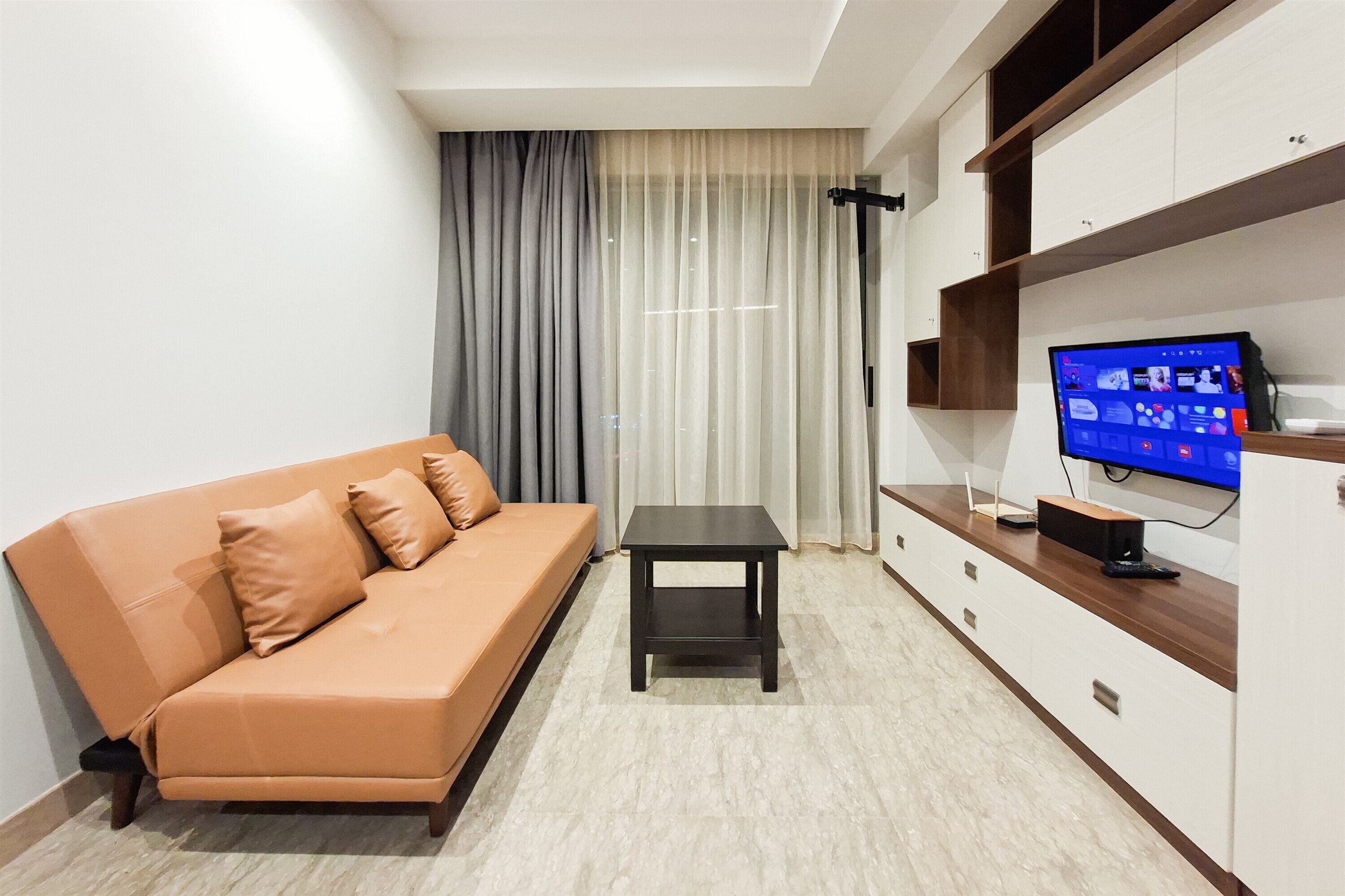 A modern living room with a sofa, a small table, and a TV on a stand.