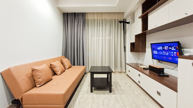 Uma sala de estar moderna com um sofá, uma mesa pequena e uma TV em um suporte.