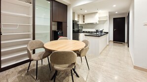 Cozinha moderna com uma ilha central, área de jantar com mesa redonda e quatro cadeiras, e porta de vidro deslizante que dá para uma varanda.