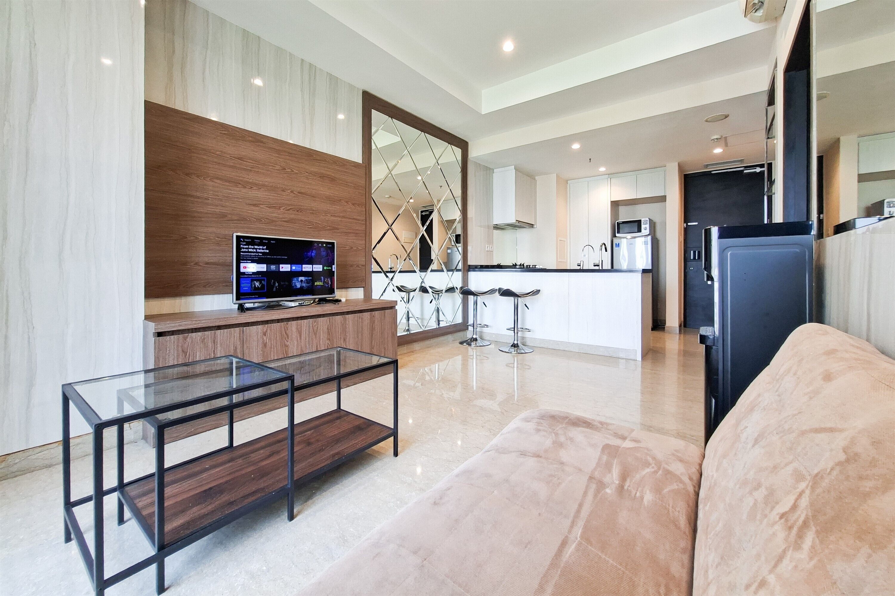 A modern kitchen with a TV, a glass coffee table, and a sofa.