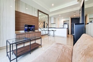 A modern kitchen with a TV, a glass coffee table, and a sofa.