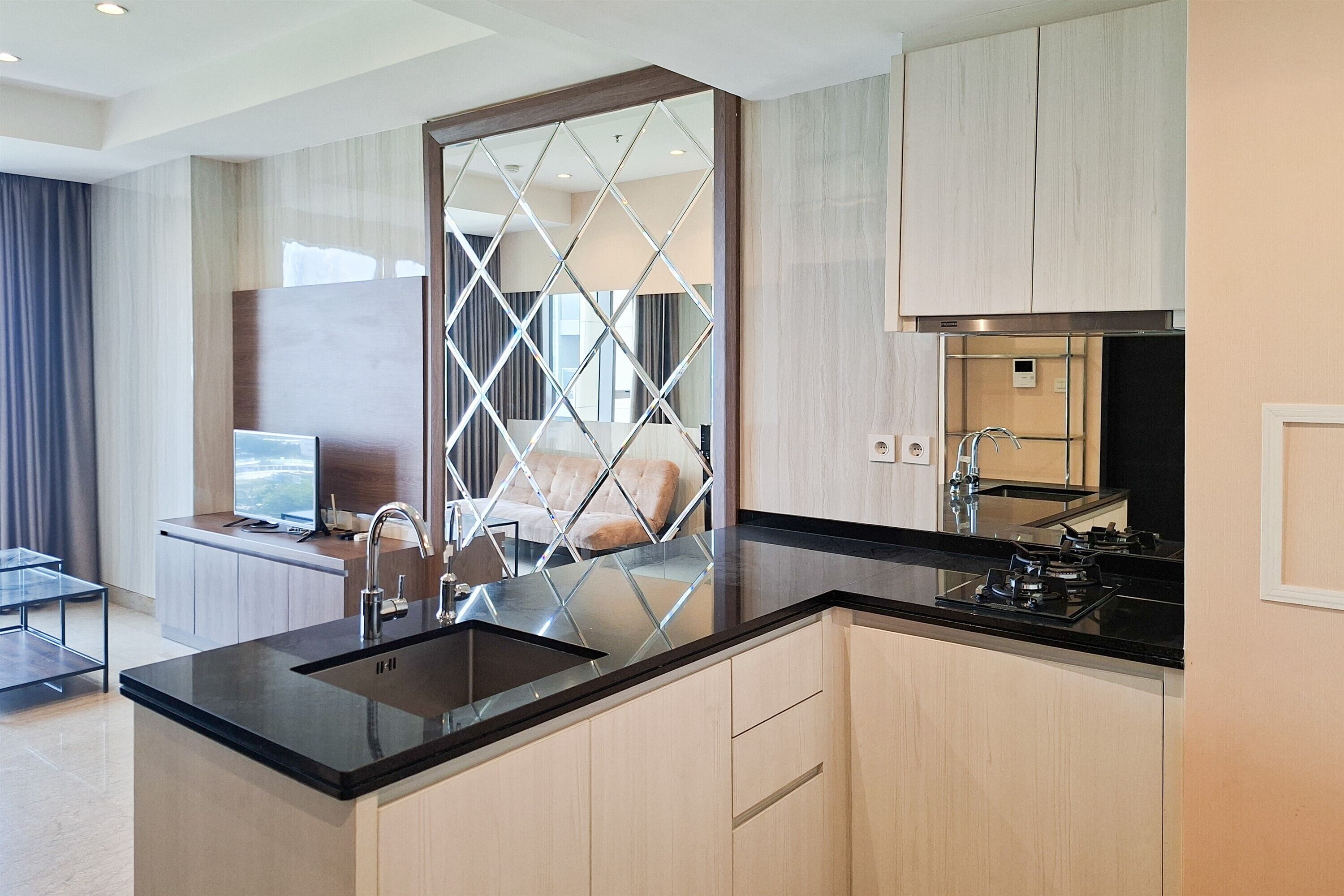 A modern kitchen with a black countertop, stainless steel appliances, and light wood cabinetry.