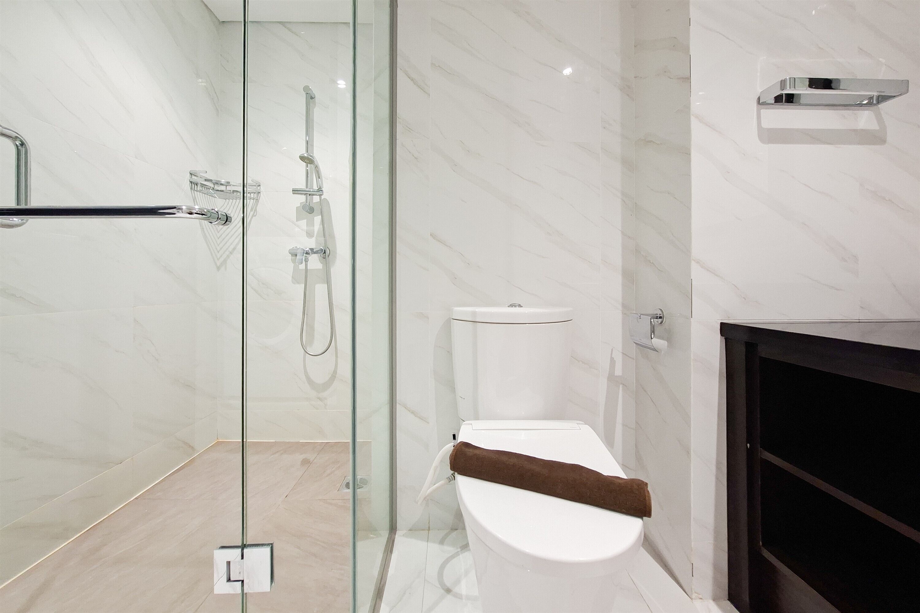 Une salle de bain moderne avec une douche à parois de verre, des toilettes blanches et un meuble en bois foncé.