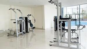 Ett rent och modernt gym med olika träningsmaskiner, stora fönster och ett klinkergolv.