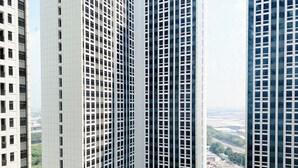 En hög byggnad med en modern arkitektonisk design, kännetecknad av ett rutmönster av fönster och en central innergård med grönska.