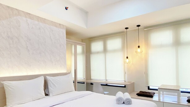 Ett modernt hotellrum med en stor säng, ett skrivbord och ett fönster med persienner.