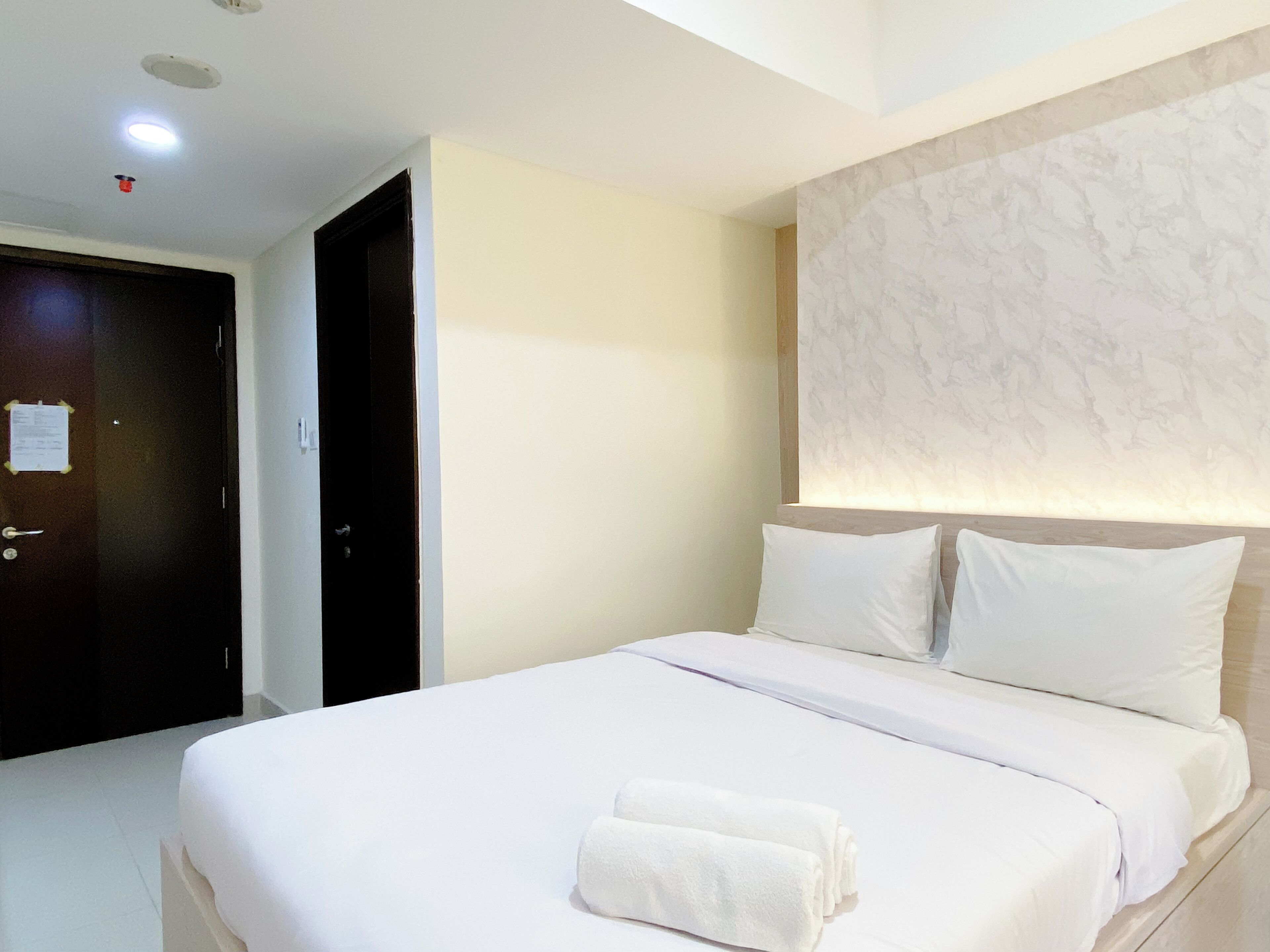 Una habitación de hotel con una cama, una puerta y una pared con una lámpara.