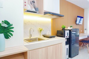 A modern kitchen with a built-in stove, a sink, and a refrigerator. - Compact Studio Near President University At Pollux Chadstone Apartment (Cikarang)