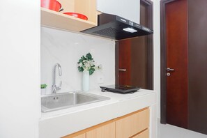 A kitchen with a stainless steel sink, a black range hood, and a white countertop. - 3 Pax Airy 2Br At Pollux Chadstone Apartment (Cikarang)