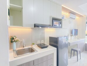 A modern kitchen with white cabinetry, a stainless steel sink, a built-in oven, and a refrigerator. - Citylight Studio At Apartment Pollux Chadstone (Cikarang)