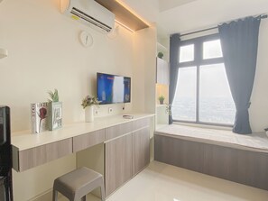 Un salon moderne avec un téléviseur à écran plat, une petite table, un banc et une fenêtre avec des rideaux.