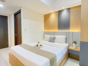 Une chambre d’hôtel moderne avec un grand lit, des tables de chevet et un luminaire fixé au mur.