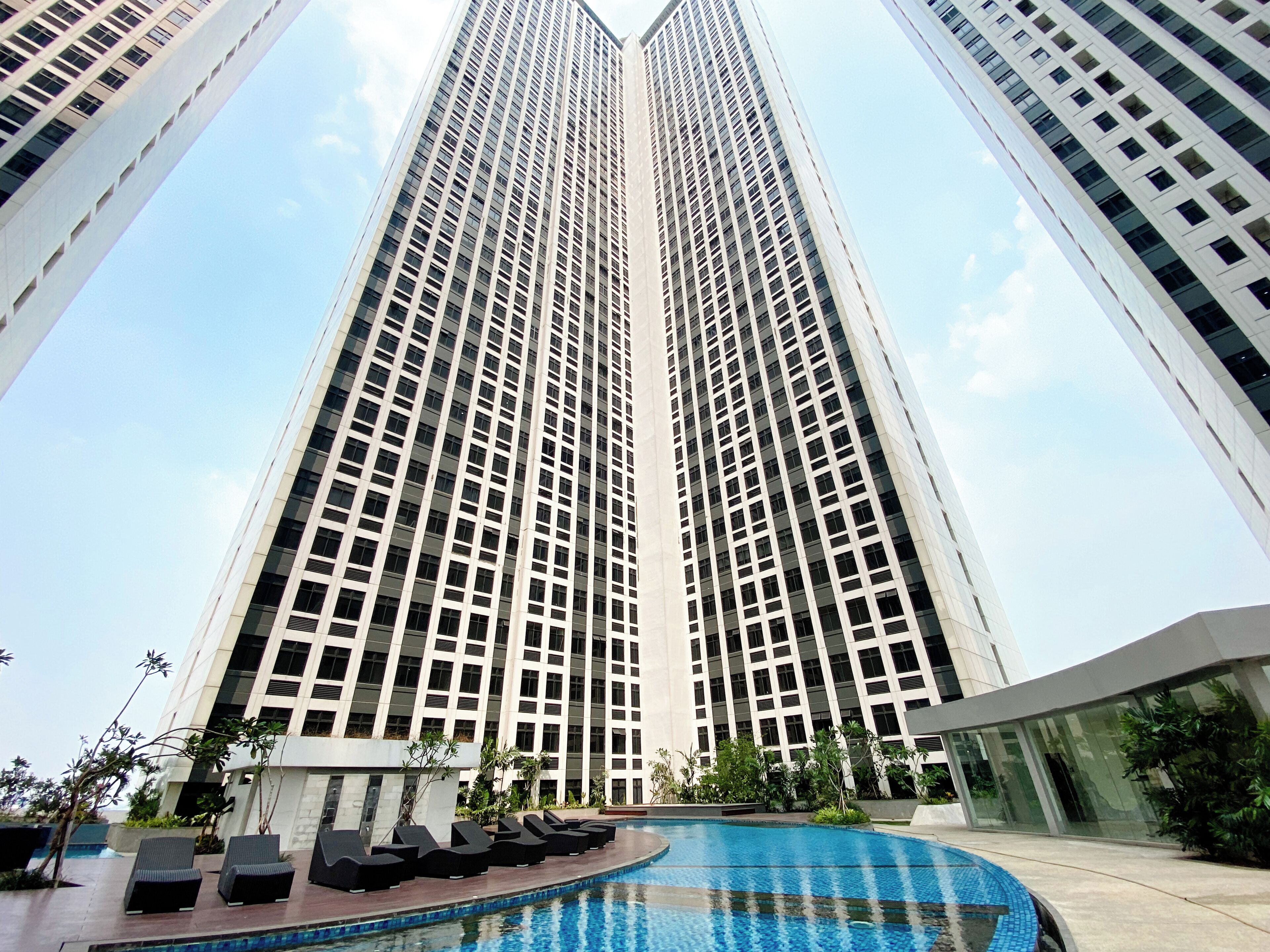 A high-rise building with a swimming pool and lounge chairs.