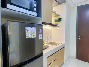 Eine kleine Küche mit Kühlschrank, Mikrowelle und eingebautem Backofen.