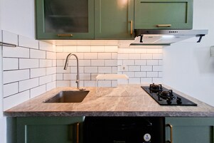 Una cocina con un lavamanos doble, estufa y armarios verdes.