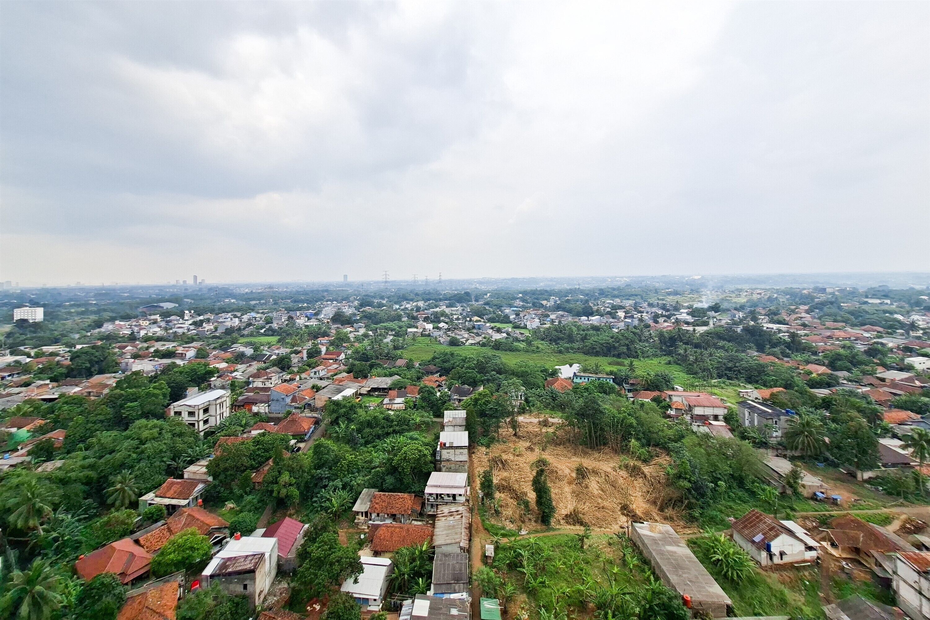 Um bairro residencial com casas, áreas verdes e um horizonte urbano ao longe.
