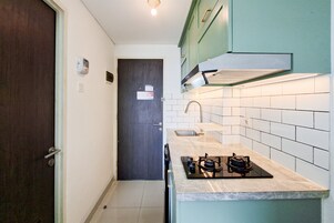 Una cocina compacta con una puerta oscura, salpicadero de azulejos blancos y una estufa a gas.