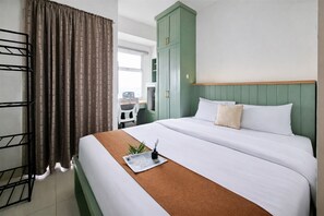 Una habitación de hotel con cama, escritorio, silla y armario.