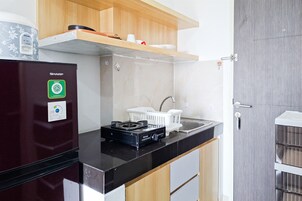 A compact kitchen with a black refrigerator, a gas stove, and a white sink.