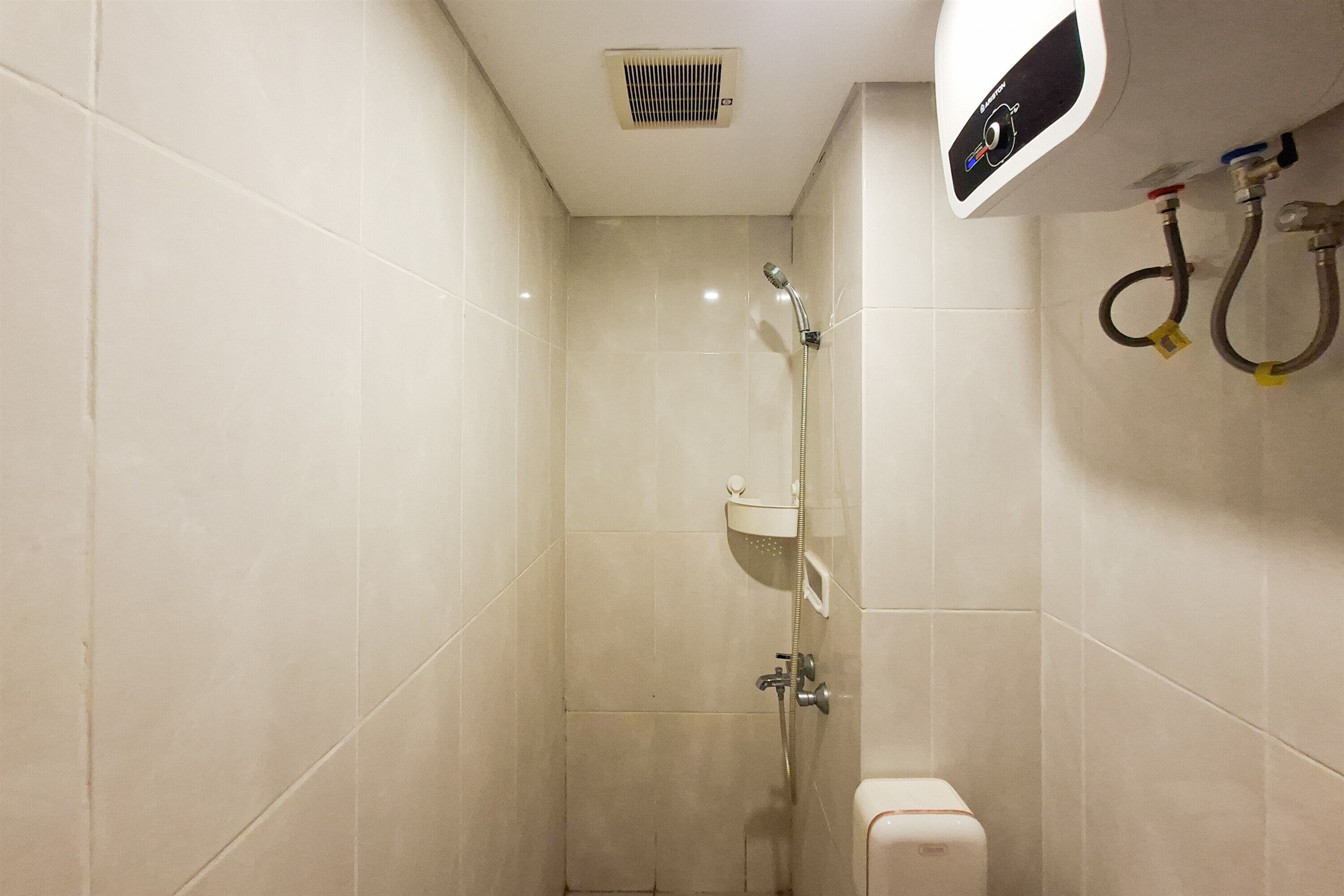 A small, tiled bathroom with a shower, a toilet, and a hand dryer.