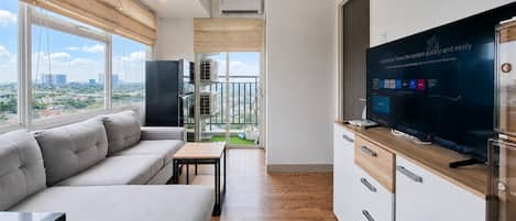 A modern living room with a sofa, TV, and a balcony with a city view.