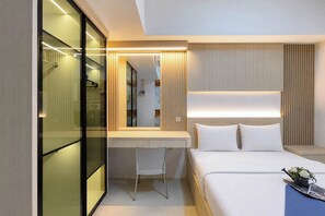 Ein modernes Hotelzimmer mit einem Bett, einem Nachttisch und einem Schreibtisch mit Stuhl.