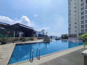 A swimming pool with metal railings, surrounded by a tiled deck and potted plants. - Good Deal Studio (No Kitchen) Apartment Skyland City Jatinangor (Sumedang)