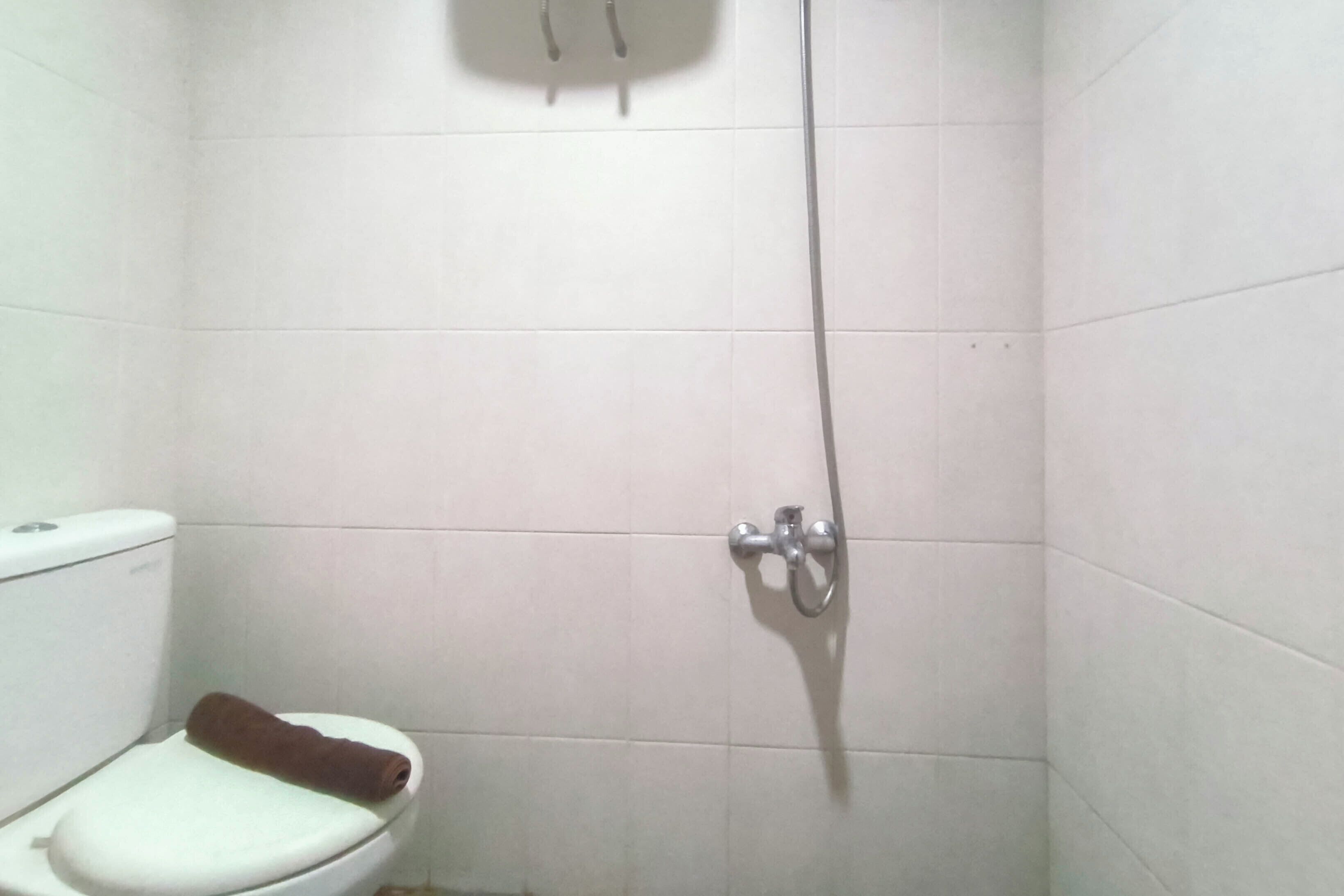 Baño pequeño con inodoro, ducha y una toalla en el asiento.