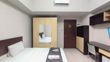 Habitación de hotel con cama, escritorio, armario y aire acondicionado.