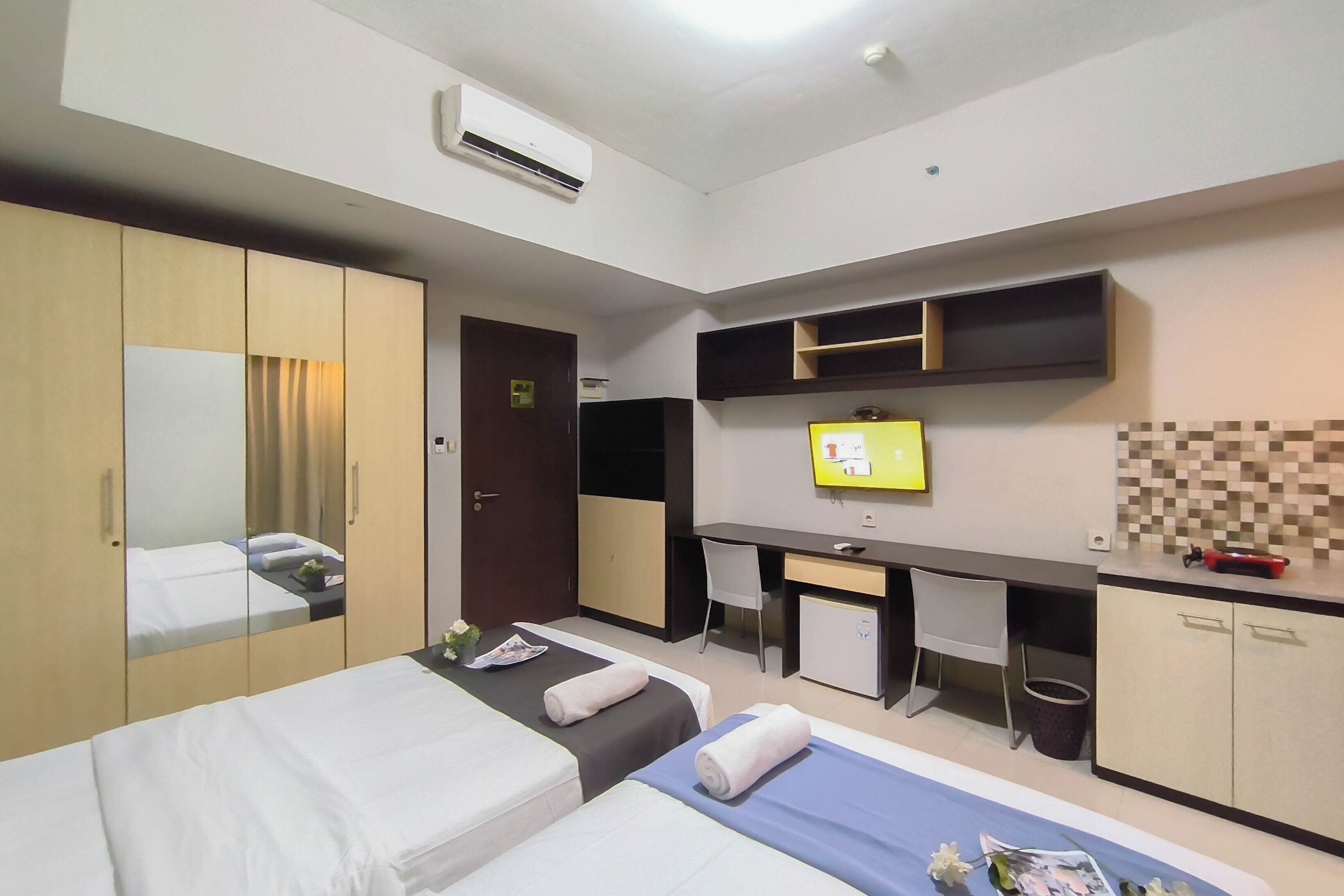 A hotel room with two beds, a desk, a television, and a wardrobe.