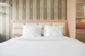 Una habitación de hotel con una cama grande, cabecera de madera y cortina estampada.