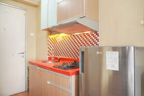 Una cocina con un refrigerador de acero inoxidable, una encimera roja y un salpicadero de azulejos.