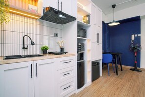 A modern kitchen with white cabinetry, a black range hood, and a built-in oven. - Restful And Serene Studio Room At Apartment Green Bay Pluit (Jakarta)