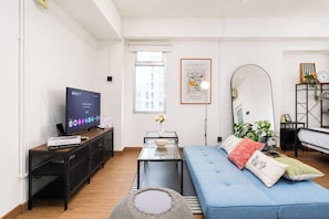 A modern living room with a television, a sofa, a coffee table, and a bookshelf. - Restful And Serene Studio Room At Apartment Green Bay Pluit (Jakarta)