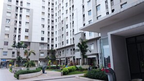 Um edifício residencial moderno, com vários andares, varandas e um pátio bem cuidado, com vegetação e esculturas decorativas.