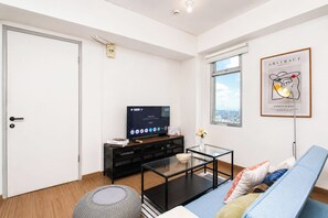 Een moderne woonkamer met een bank, een salontafel, een televisie en een kunstwerk in een lijst aan de muur.