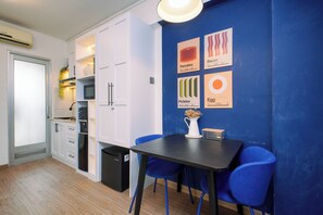 Eine moderne Küche mit weißen Schränken, einem schwarzen Kühlschrank und einem Essbereich mit Tisch und blauen Stühlen.