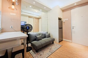 Um espaço de estar compacto com sofá, uma mesinha, um ventilador e uma porta.