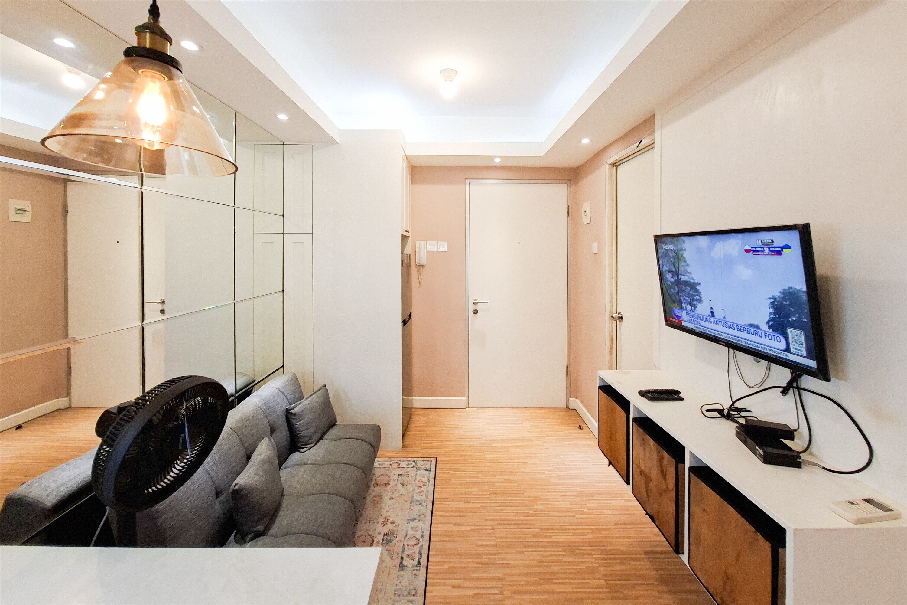 Una sala moderna con un sofá, una televisión y un ventilador.