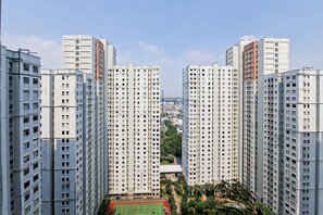 Um edifício residencial alto, com vários andares, um pátio central com vegetação e vista clara do horizonte urbano.