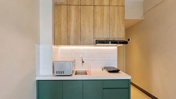Una cocina compacta con encimera blanca, horno integrado y microondas.